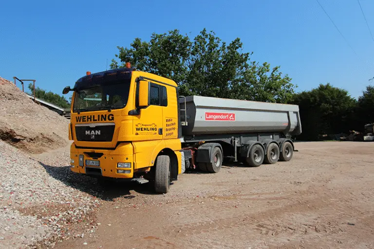 Ein Kipplaster steht vor einem Erdhaufen